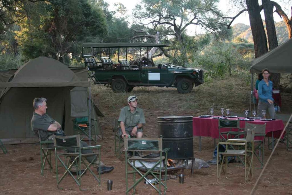 3 Gäste sitzen auf Campingstühlen im Luxus-Safari-Camp