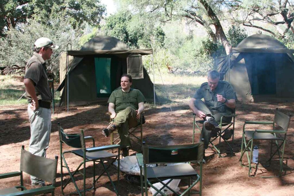 Drei Männer sitzen zusammen im Safari-Luxus-Camp